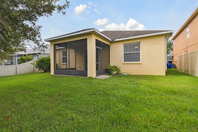 rear view of house with a yard and a sunroom