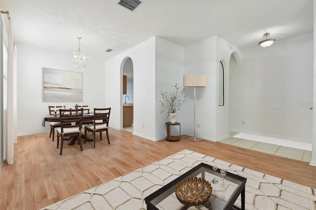 dining area with light hardwood / wood-style floors and an inviting chandelier