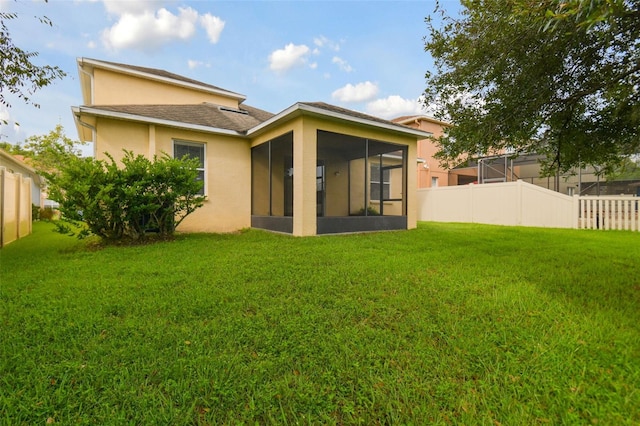 back of house with a yard and a sunroom