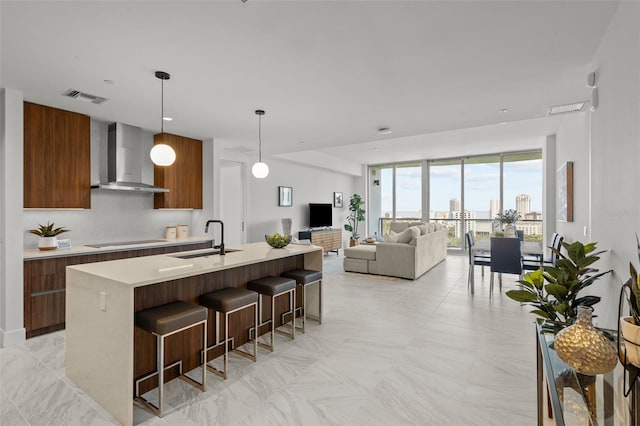 kitchen featuring black electric stovetop, light countertops, a sink, modern cabinets, and wall chimney exhaust hood