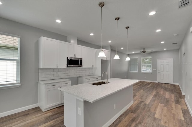 kitchen with pendant lighting, a center island with sink, plenty of natural light, and white cabinetry