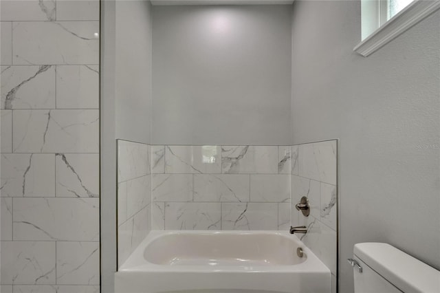 bathroom featuring tiled shower / bath combo and toilet