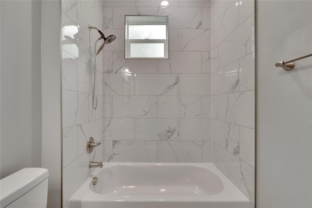 bathroom featuring tiled shower / bath combo and toilet