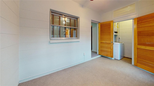 carpeted empty room featuring washer / dryer