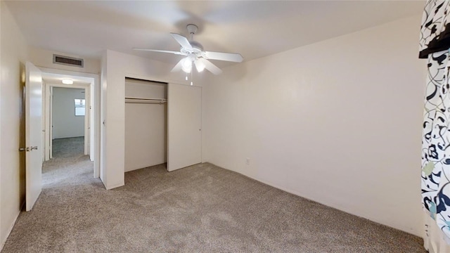 unfurnished bedroom featuring ceiling fan, a closet, and light colored carpet