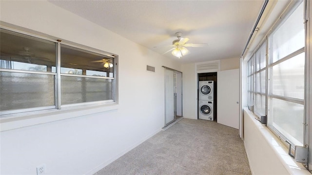 unfurnished sunroom featuring ceiling fan and stacked washer and clothes dryer