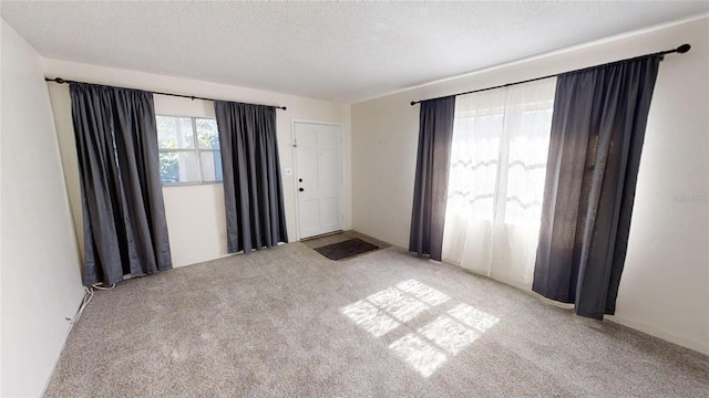 carpeted empty room featuring a textured ceiling