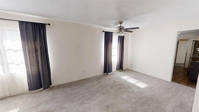 spare room featuring ceiling fan, light colored carpet, and a textured ceiling