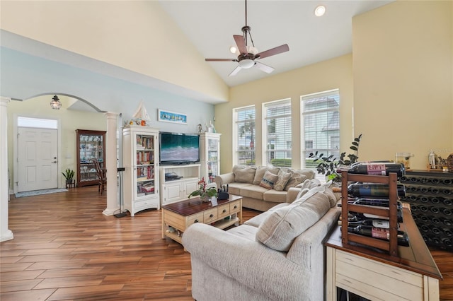 living room with ceiling fan, ornate columns, hardwood / wood-style floors, and high vaulted ceiling