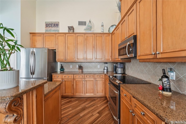 kitchen featuring appliances with stainless steel finishes, tasteful backsplash, dark wood-type flooring, and stone counters