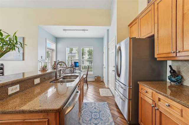 kitchen with sink, stone counters, track lighting, stainless steel appliances, and light hardwood / wood-style floors