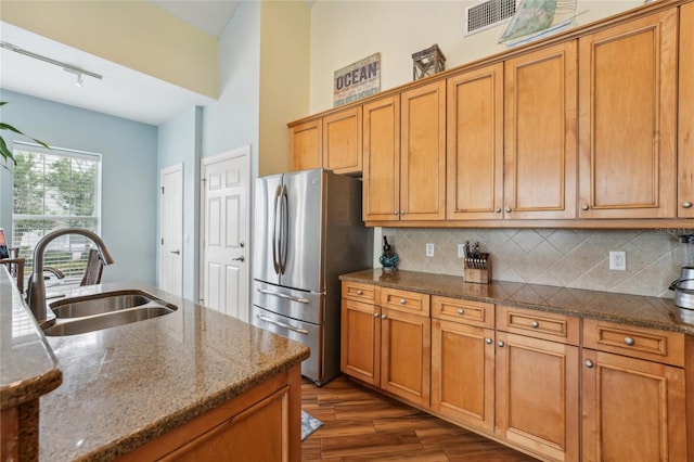 kitchen with stainless steel fridge, sink, tasteful backsplash, dark hardwood / wood-style floors, and dark stone counters