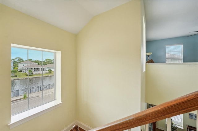 hallway featuring a water view, lofted ceiling, and a wealth of natural light