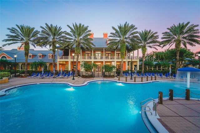 pool at dusk featuring a patio area and pool water feature