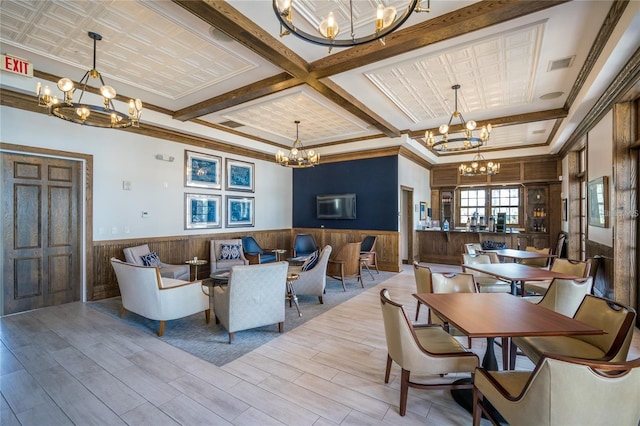 dining area featuring coffered ceiling, ornamental molding, light wood-type flooring, and a chandelier