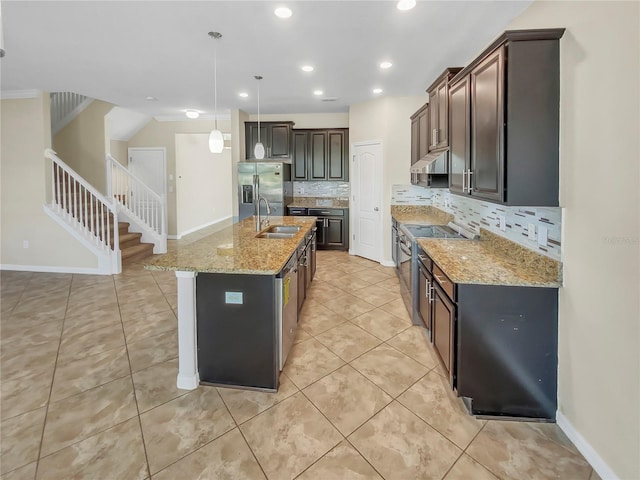 kitchen featuring tasteful backsplash, dark brown cabinets, decorative light fixtures, a center island with sink, and sink