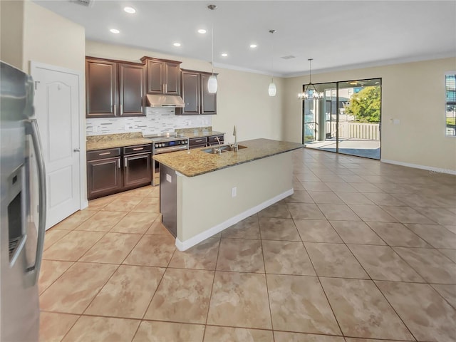 kitchen with appliances with stainless steel finishes, decorative backsplash, an island with sink, light stone countertops, and sink