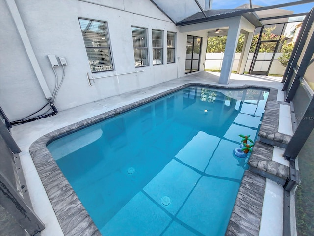 view of swimming pool featuring glass enclosure and a patio area