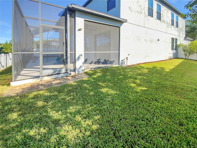 back of house featuring a sunroom, a lawn, and a lanai