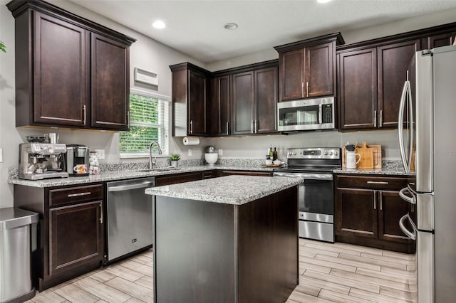 kitchen with stainless steel appliances, a center island, sink, and light hardwood / wood-style flooring