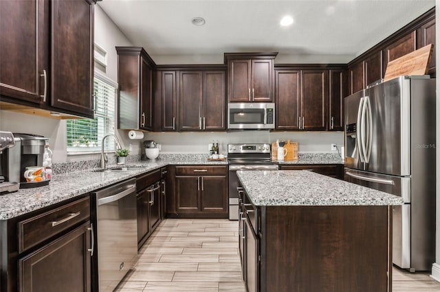 kitchen with dark brown cabinets, appliances with stainless steel finishes, sink, and a kitchen island