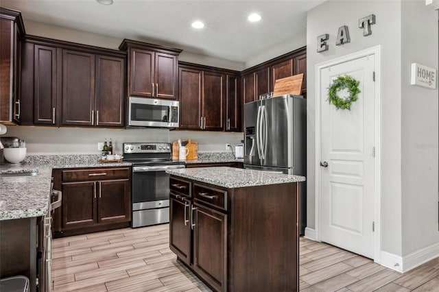 kitchen featuring appliances with stainless steel finishes, dark brown cabinetry, light hardwood / wood-style floors, and a kitchen island