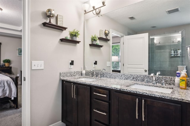 bathroom featuring a textured ceiling, a shower with door, and vanity