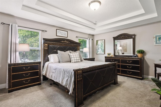 carpeted bedroom with a textured ceiling and a raised ceiling