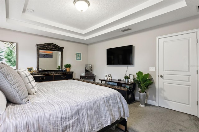 bedroom featuring carpet, a textured ceiling, and a tray ceiling