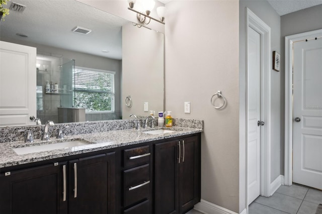 bathroom featuring vanity, an enclosed shower, a textured ceiling, a notable chandelier, and tile patterned flooring