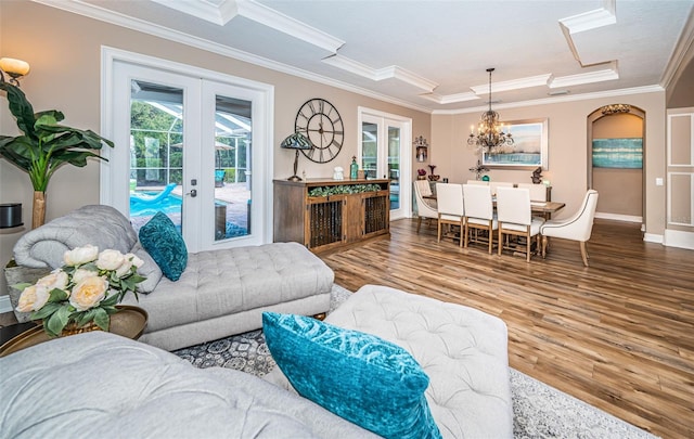 living room featuring wood-type flooring, ornamental molding, an inviting chandelier, and french doors