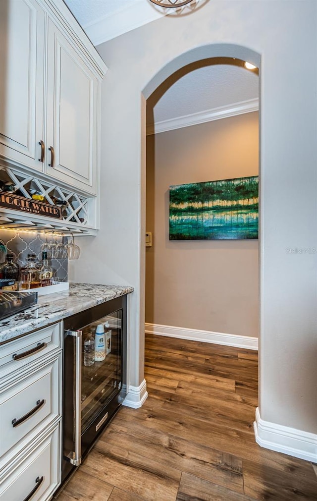 kitchen featuring light stone counters, white cabinets, light wood-type flooring, and crown molding