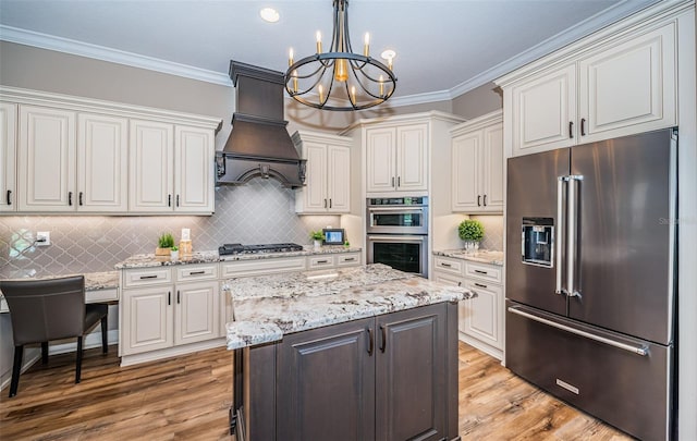 kitchen with appliances with stainless steel finishes, hanging light fixtures, an inviting chandelier, and white cabinets