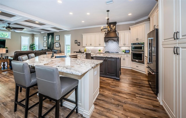 kitchen featuring ceiling fan, decorative light fixtures, a large island with sink, appliances with stainless steel finishes, and dark hardwood / wood-style flooring