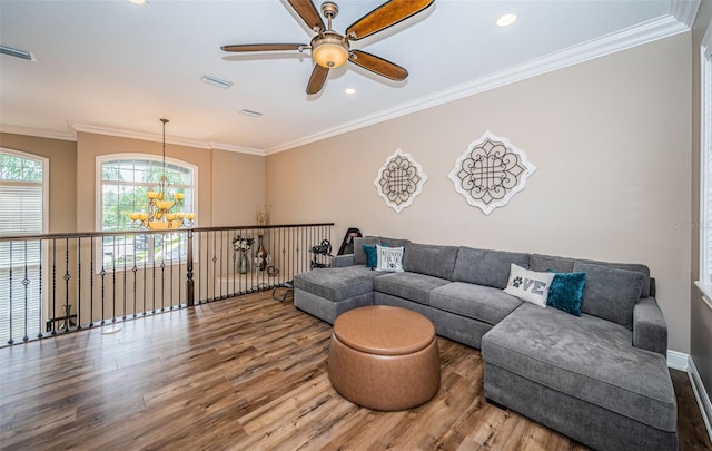 living room featuring hardwood / wood-style flooring, ceiling fan with notable chandelier, and ornamental molding