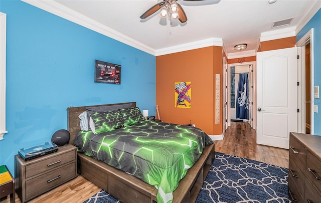 bedroom with ceiling fan, ornamental molding, and dark wood-type flooring