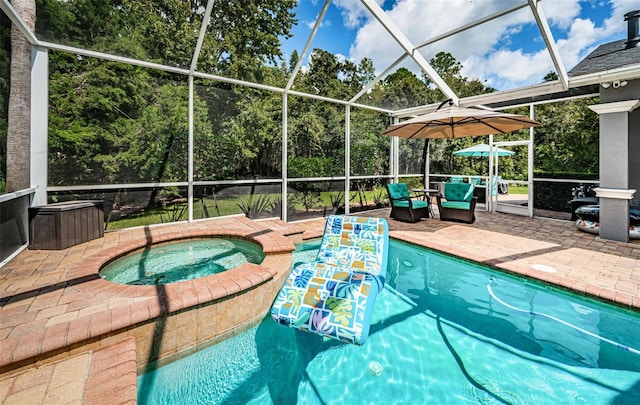 view of swimming pool featuring glass enclosure, an in ground hot tub, and a patio