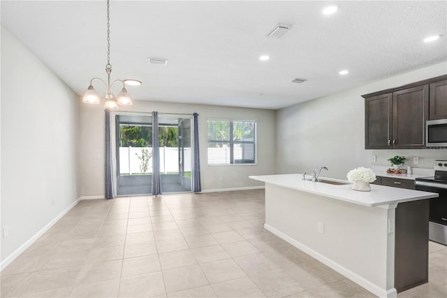 kitchen with a chandelier, a kitchen island with sink, sink, appliances with stainless steel finishes, and dark brown cabinetry