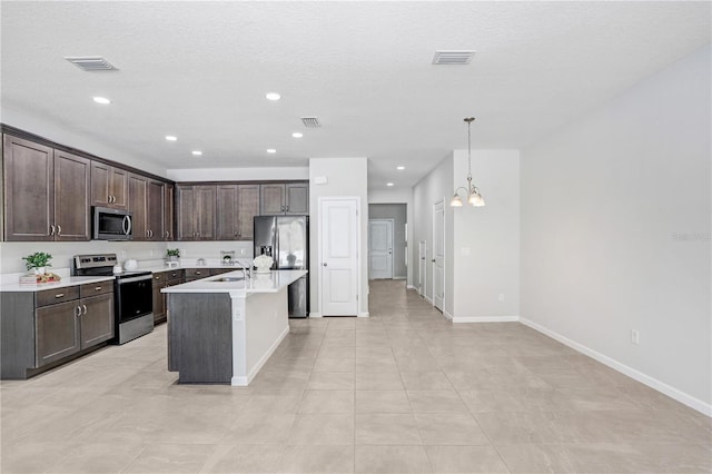 kitchen with dark brown cabinets, sink, hanging light fixtures, stainless steel appliances, and a center island with sink