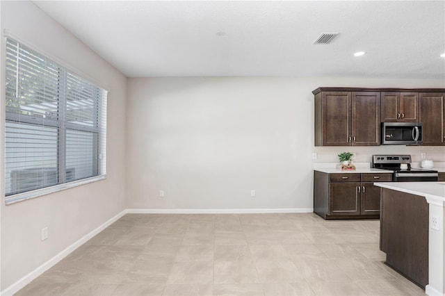 kitchen with dark brown cabinetry and appliances with stainless steel finishes