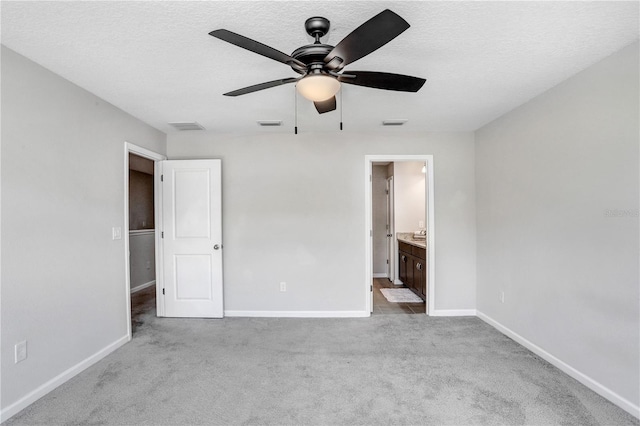 unfurnished bedroom with ceiling fan, ensuite bath, and light carpet