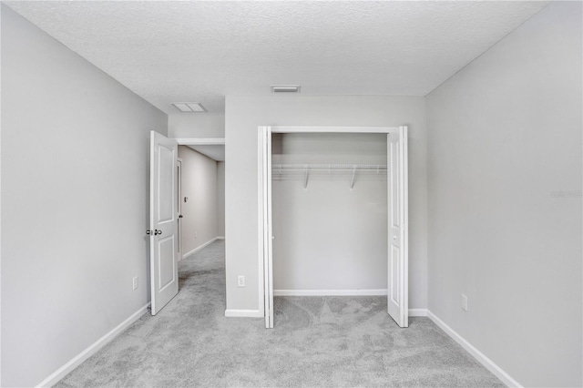 unfurnished bedroom with a closet, light colored carpet, and a textured ceiling