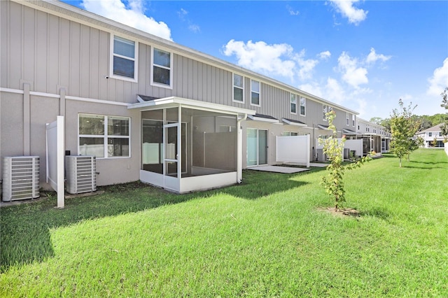 rear view of property featuring a lawn, a sunroom, and central air condition unit