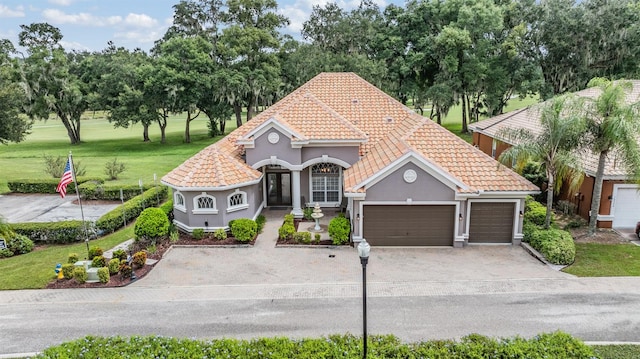 view of front facade featuring a garage, a tile roof, driveway, stucco siding, and a front yard