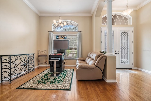 entryway featuring ornamental molding, a notable chandelier, decorative columns, and hardwood / wood-style floors