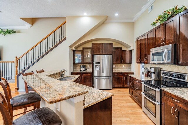 kitchen featuring light hardwood / wood-style floors, sink, a center island with sink, appliances with stainless steel finishes, and a kitchen bar