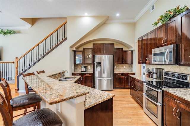 kitchen featuring visible vents, ornamental molding, stainless steel appliances, a sink, and a kitchen breakfast bar