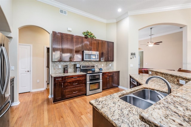 kitchen featuring ceiling fan, light stone counters, sink, light hardwood / wood-style flooring, and stainless steel appliances