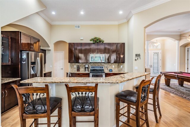 kitchen with light stone counters, a kitchen island, appliances with stainless steel finishes, pool table, and light wood-type flooring