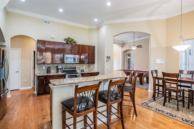 kitchen featuring pendant lighting, light wood-type flooring, an island with sink, stainless steel appliances, and ceiling fan